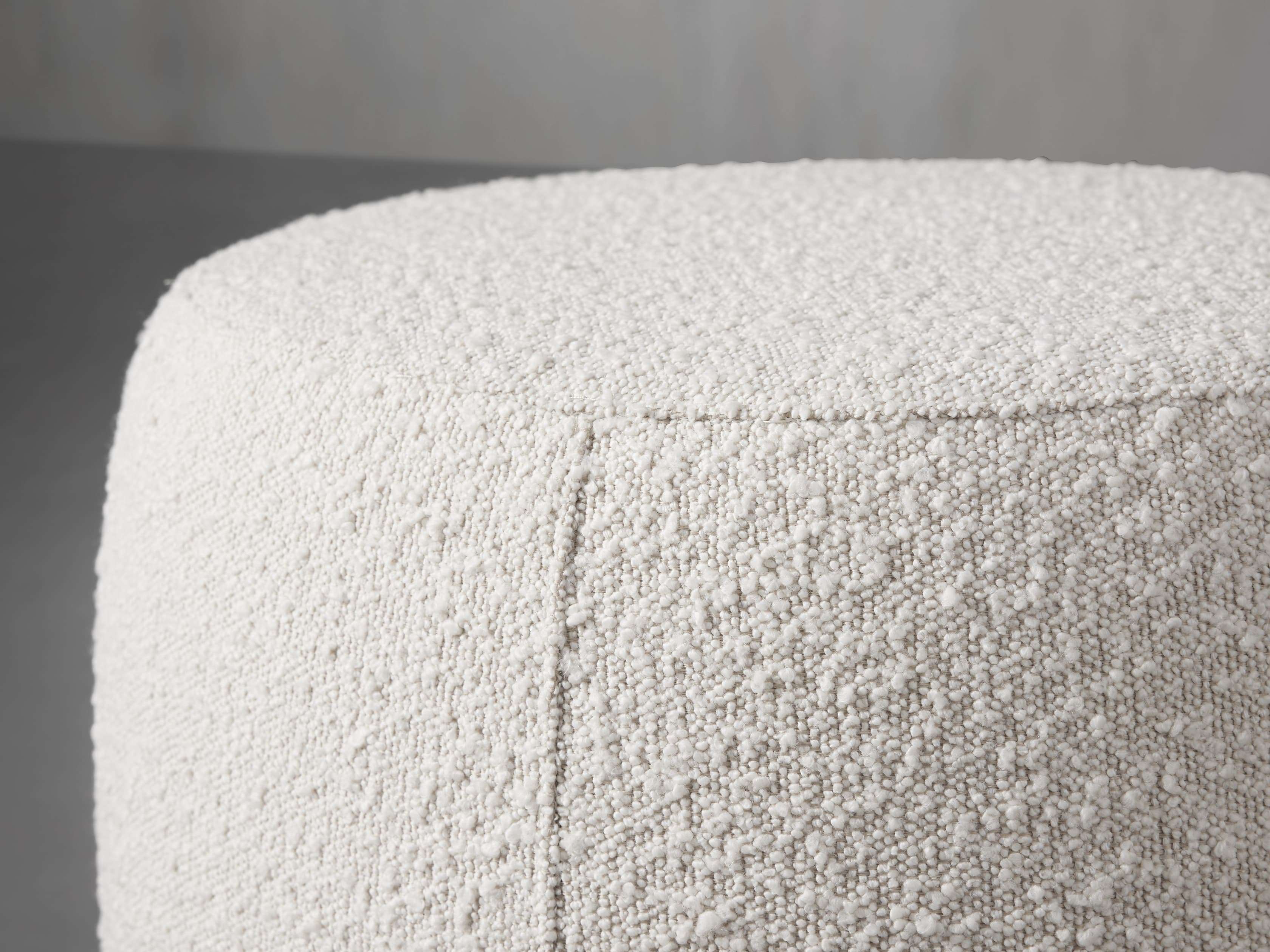 Close-up view of the Ryles Ottoman in Upholstered Natural fabric, showcasing its soft plush texture and seamless stitching.