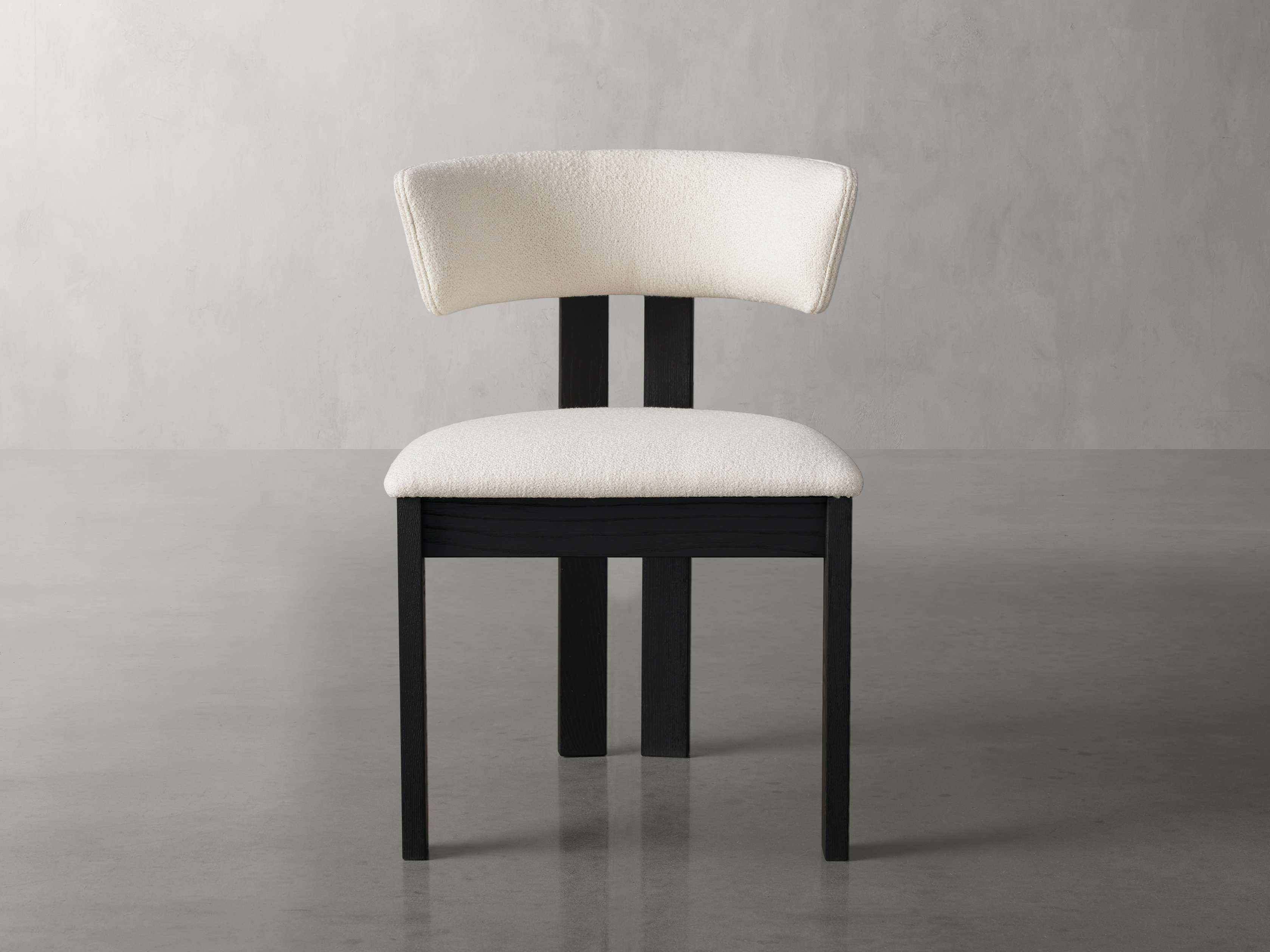 A contemporary dining side chair with a white upholstered seat and backrest, featuring a dark ash wood frame on a polished surface.