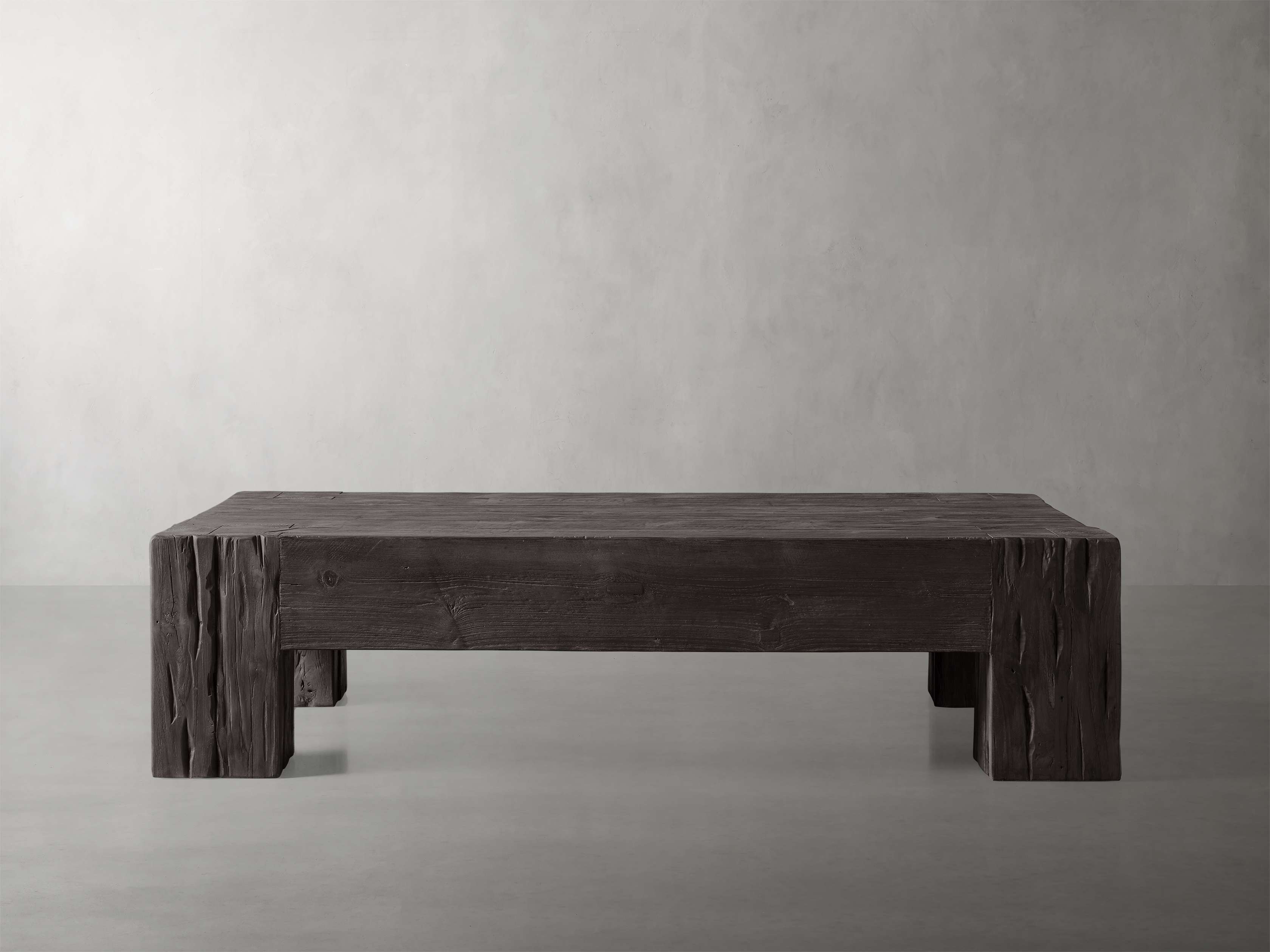 A rustic wooden coffee table with a rectangular shape, thick legs, and a natural gray finish, shown against a neutral background.