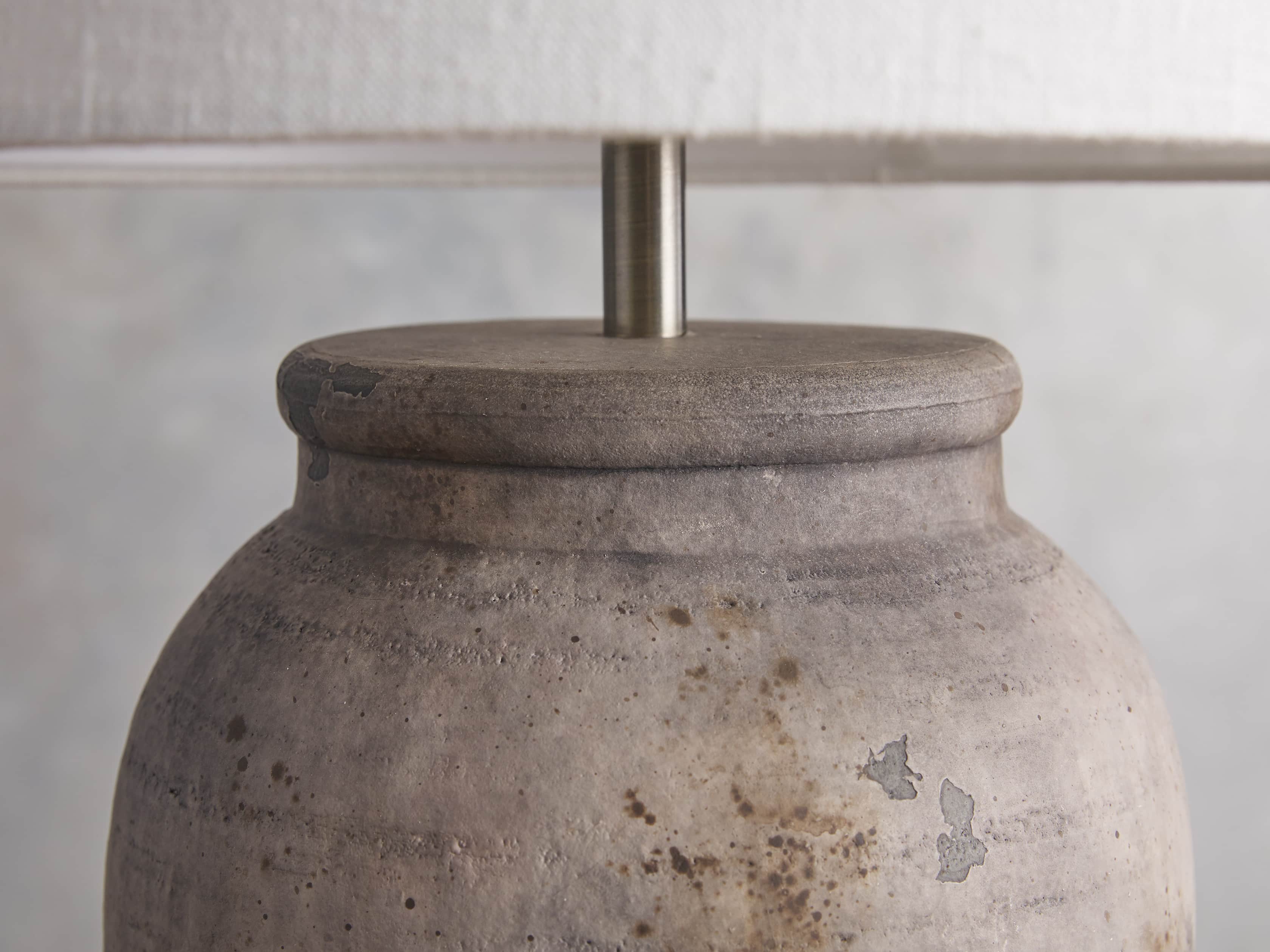 Close-up of the Thornton Table Lamp featuring a ceramic gray urn-shaped base with distressed detailing and a white drum shade.