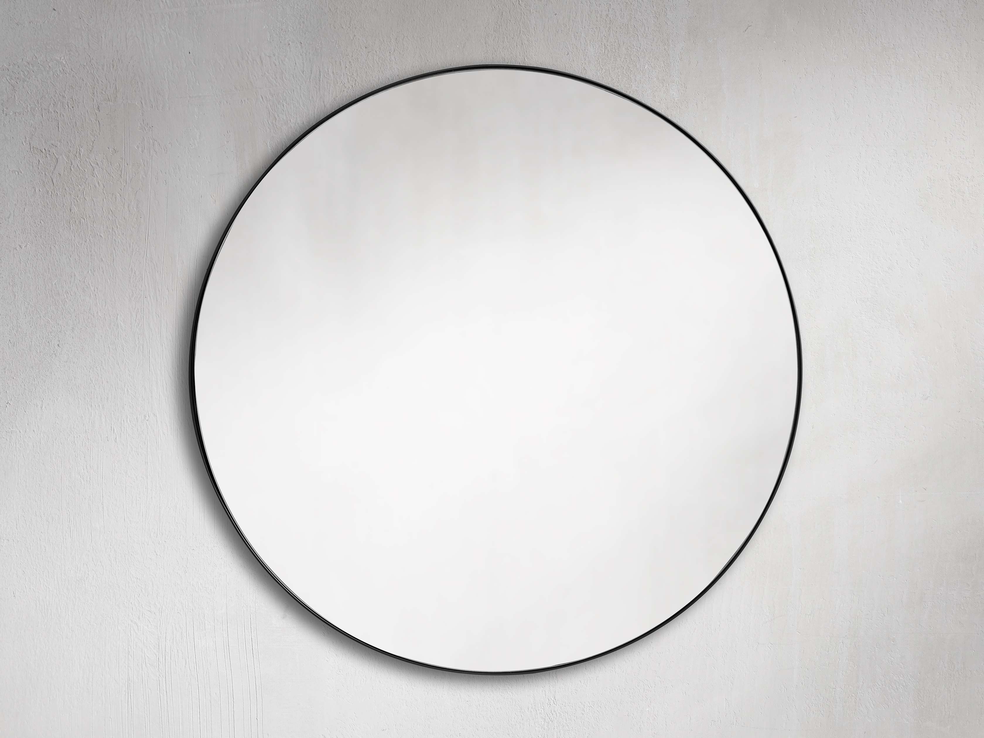 A round mirror with a minimalist black steel frame, mounted on a textured light-colored wall, showcasing its modern design.