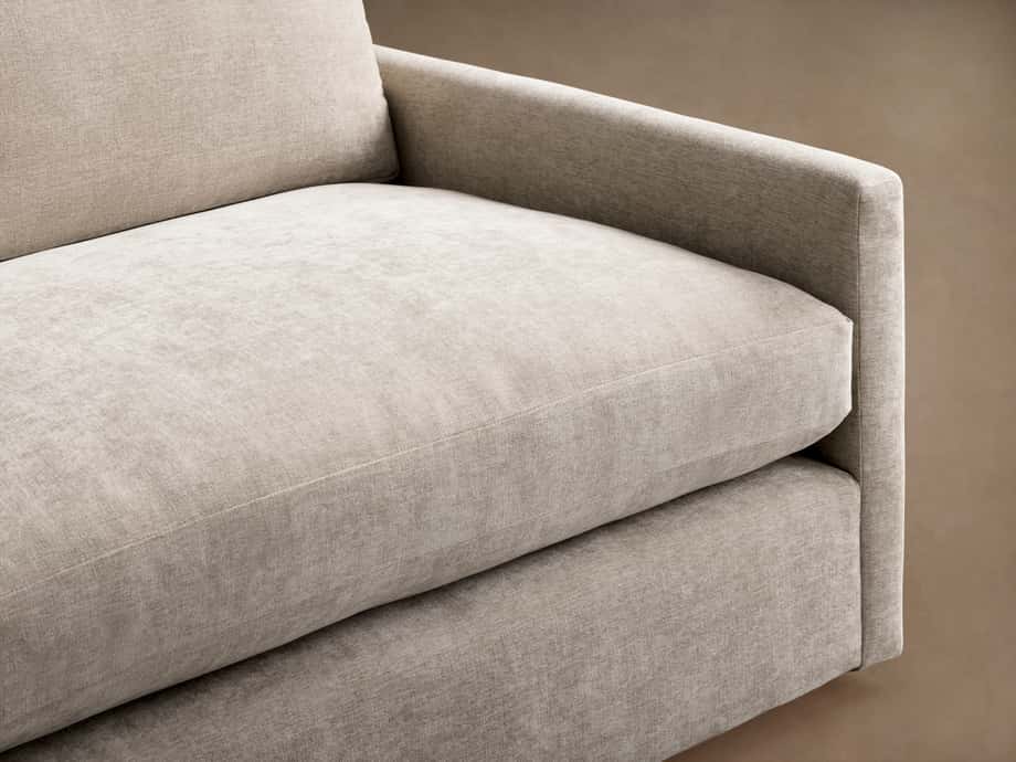 Close-up of a Kipton Slim Arm Sofa's right side, showing a slim armrest and two plush, light beige fabric seat cushions.