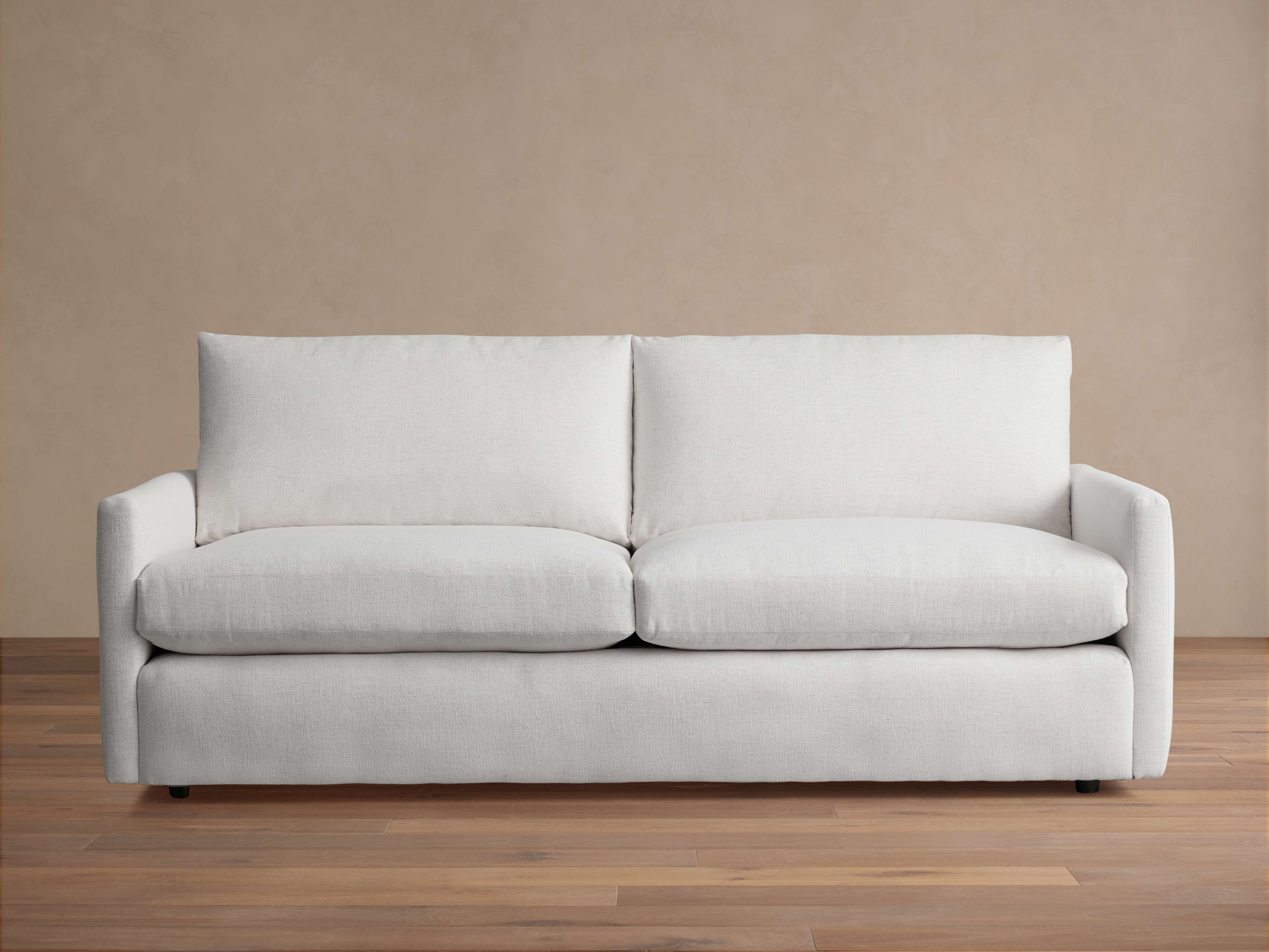 Kipton Sofa in light beige fabric with plush seat cushions and backrests, straight armrests, and wooden floor setting.