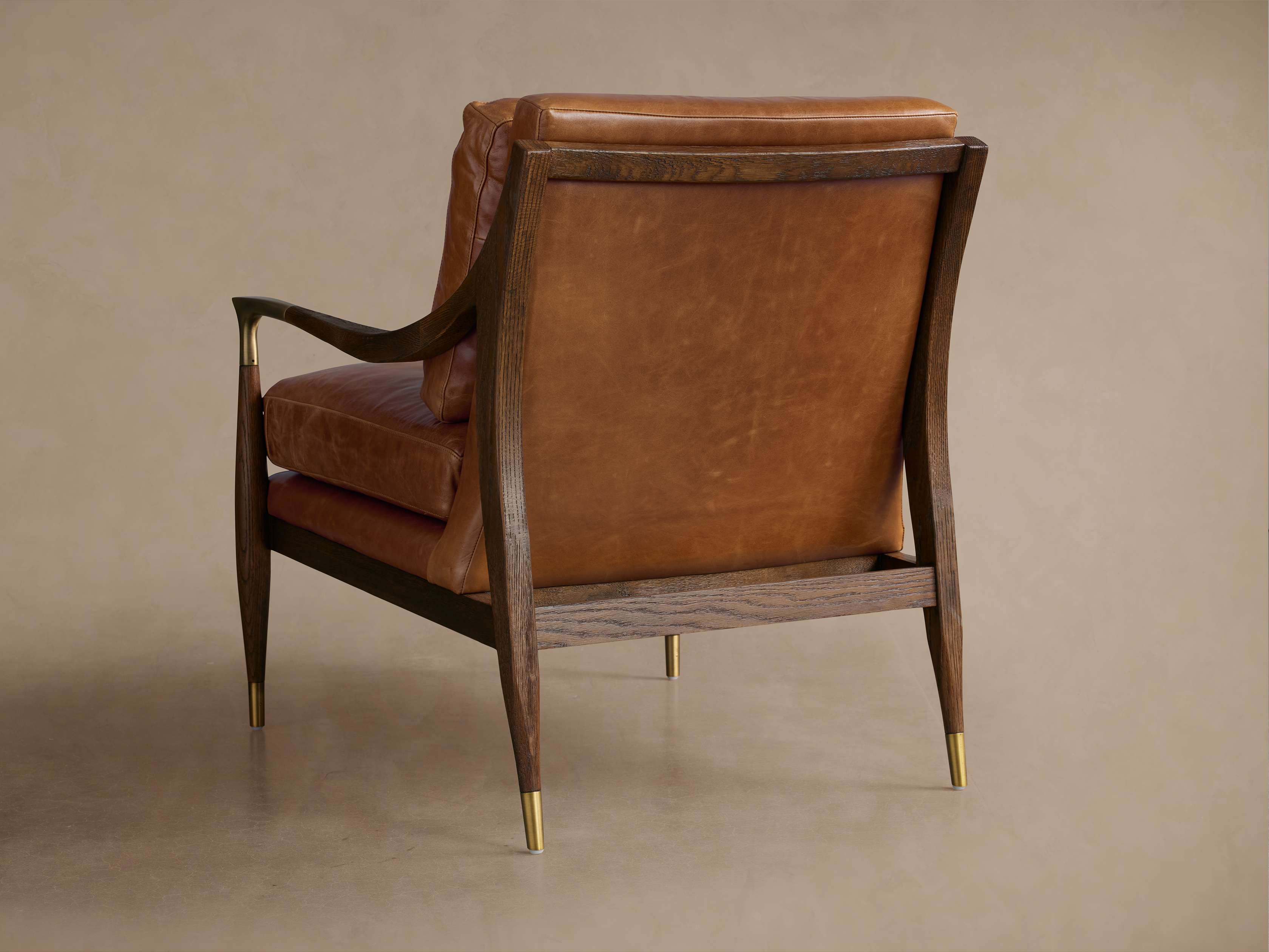 Brown leather chair with wooden frame and gold accents, rear view