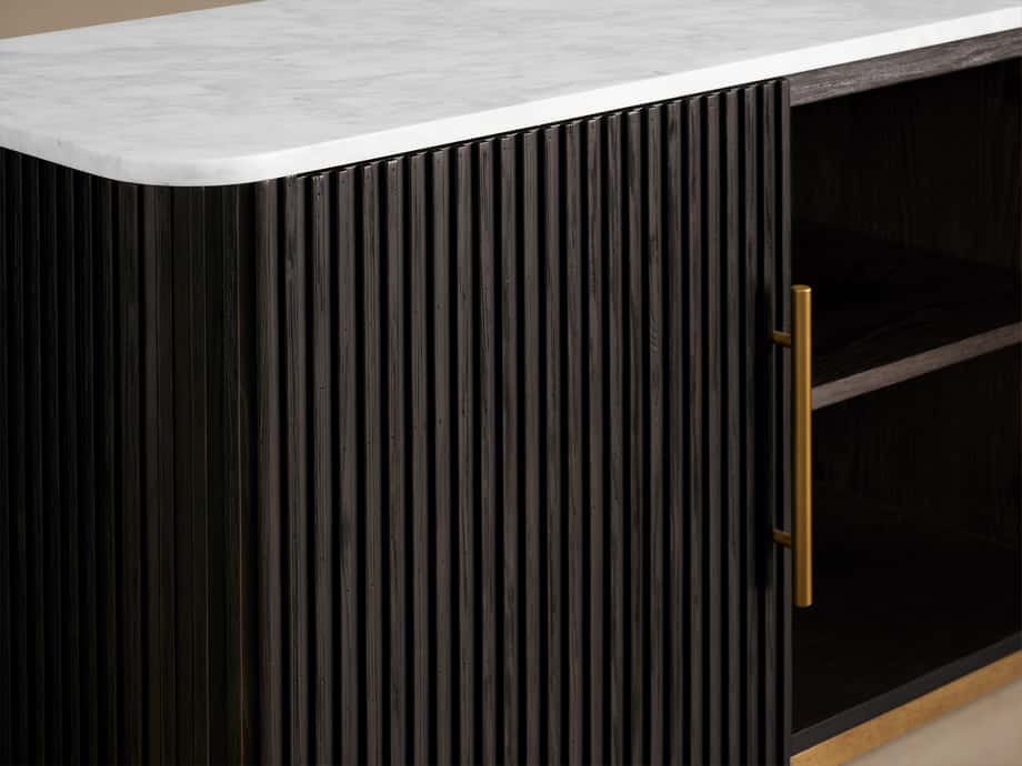 Finnley Media Console with a white marble top and black vertical slatted wood front. Brass handle on the right side.