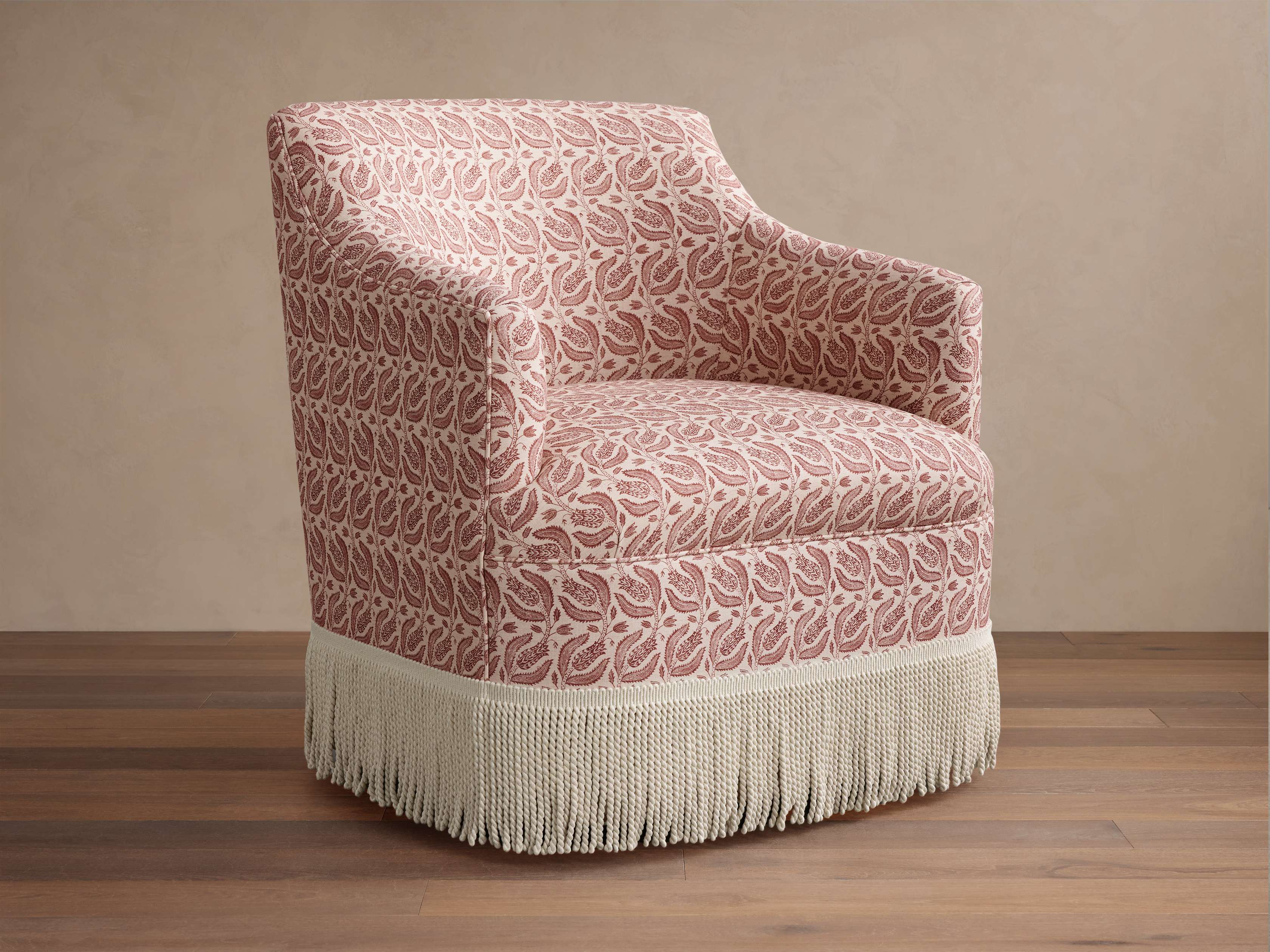 Chair with pink and white paisley fabric and white fringe on wooden floor